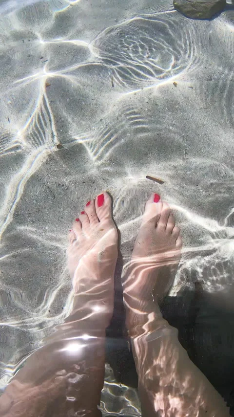 Vertical slow motion view of female feet underwater in crystal clear sea Stock Footage 337243865