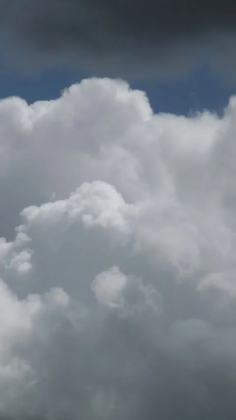 Vertical slow-motion view of a white cumulus cloud with a dark top against .. Stock Footage 342043859