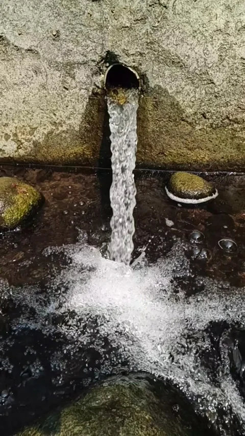 Vertical slow motion of water flows from a drain pipe into a canal Stock-Footage 347103527