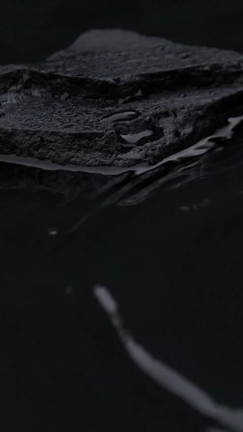 Vertical slow motion of water surface splashes, waves, ripples with black stone Stock Footage 253974197