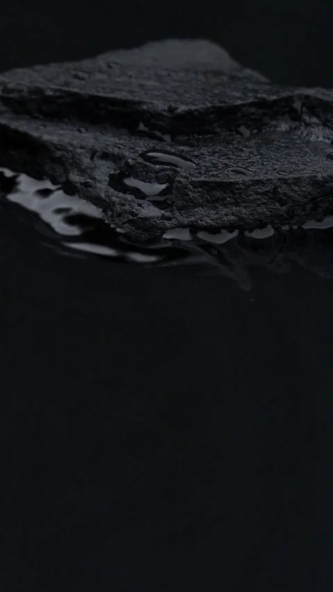 Vertical slow motion of water surface splashes, waves, ripples with black stone Stock Footage 255187582
