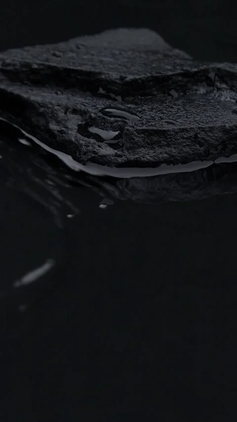 Vertical slow motion of water surface splashes, waves, ripples with black stone Stock Footage 259860392