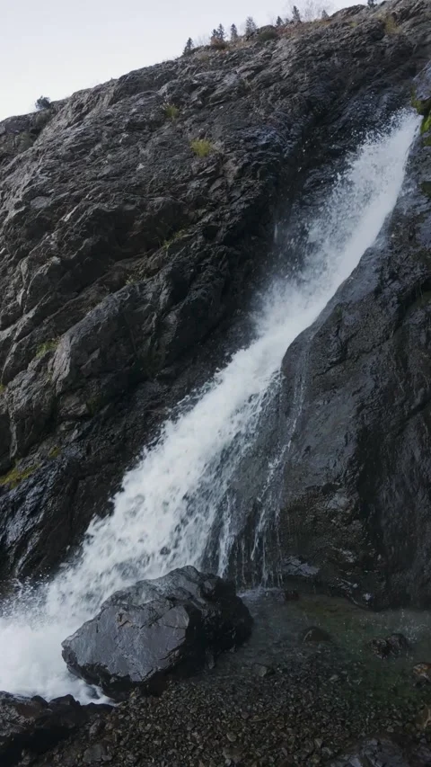 Vertical Slow Motion of Waterfall Cascading Down Dark Rocky Cliff Stock Footage 330441087