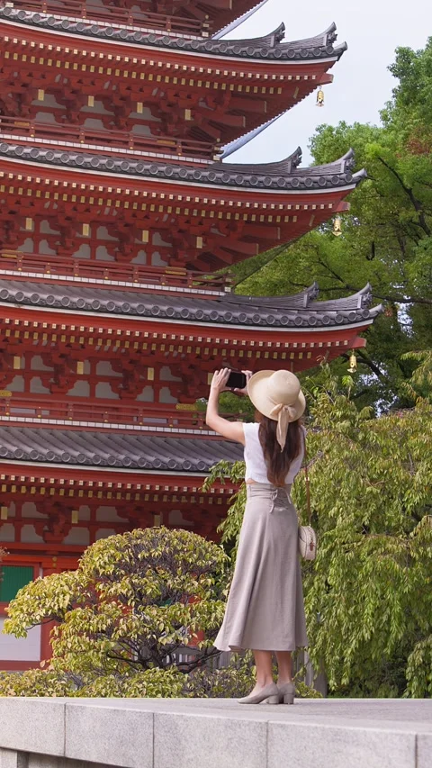 Vertical slow motion of woman visiting Japanese temple near red pagoda Stock Footage 342383406