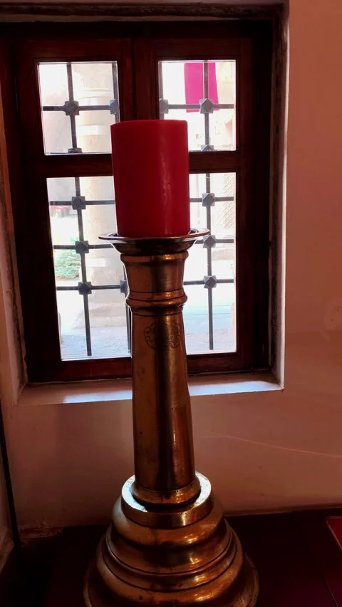 Vertical slow pan from left to right of a large red candle on an antique brass Stock Footage 334029407