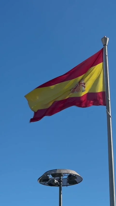 Vertical Slowmotion a worn Spanish flag waves from a pole, torn fabric. Stock Footage 307571407