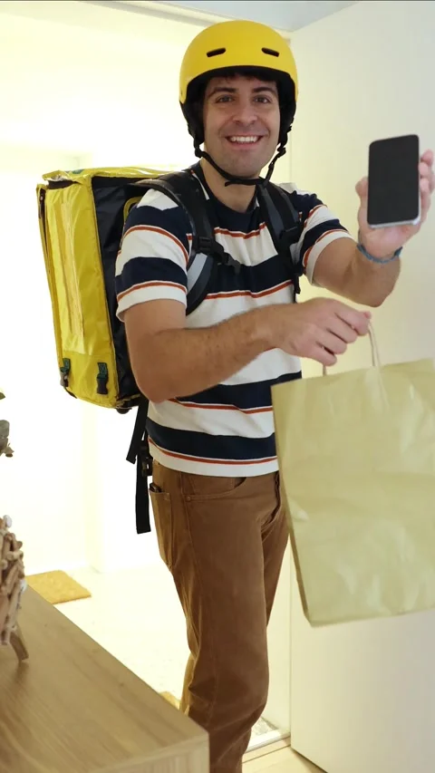 Vertical Smiling delivery man showing a smartphone screen Stock Footage 318096165