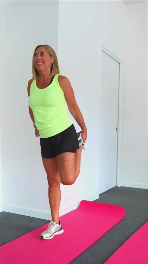 Vertical Smiling elderly female athlete stretching leg muscles on mat durin.. Stock Footage 285092407