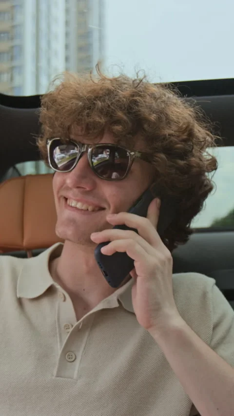 Vertical of Smiling Man Talking on Smartphone in Convertible Car Stock Footage 343375714