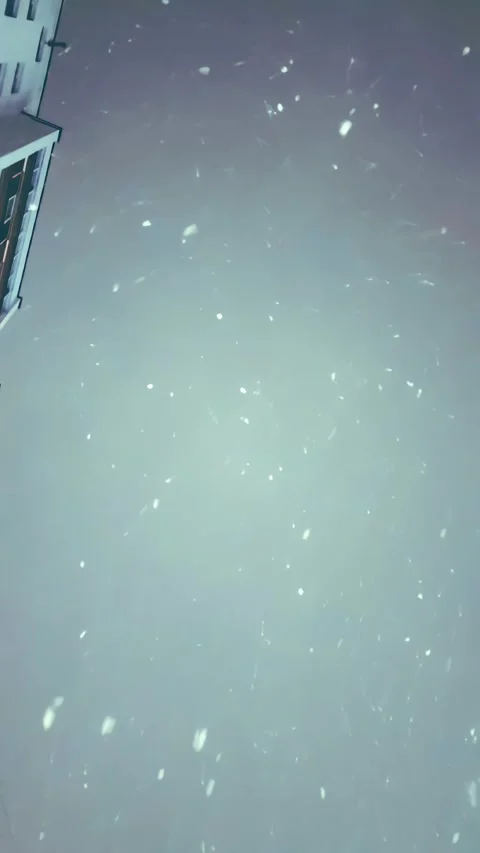 Vertical snowfall over city streets at night with glowing urban lights Stock Footage 345516585