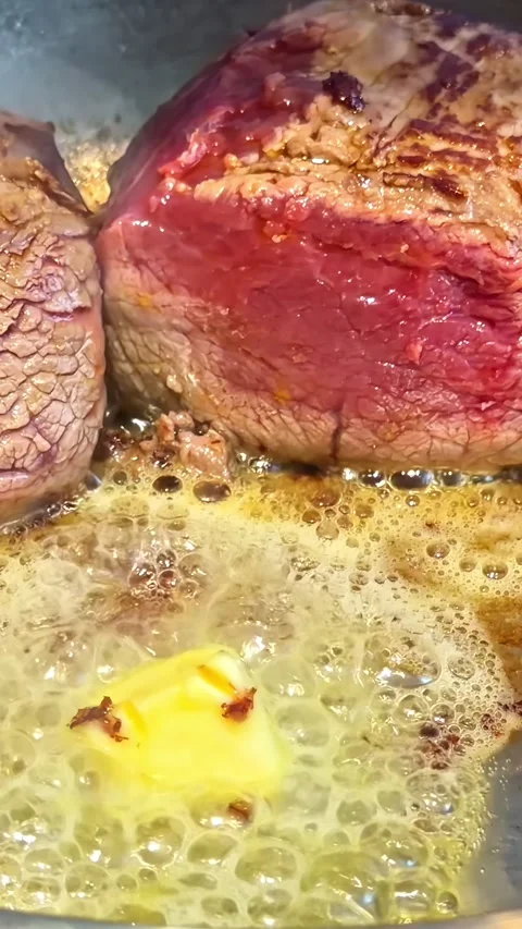 Vertical social ratio close-up video of steaks sizzling in butter on a frying Stock Footage 336946059