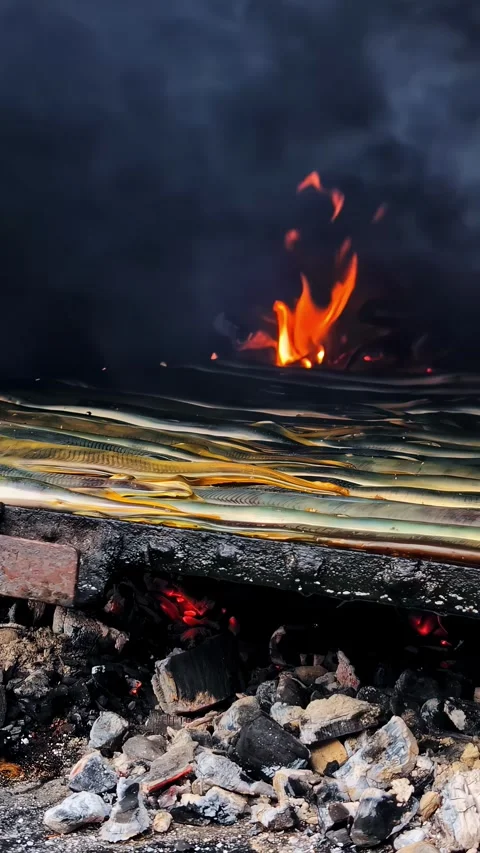 Vertical social ratio video of fish cooking on a coal grill. Flames move in the Stock Footage 336945710
