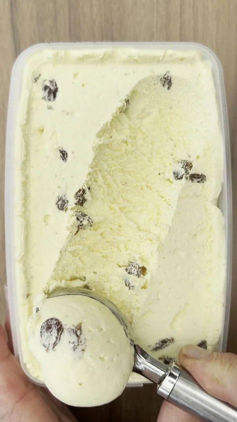 Vertical - A spoon tool scooping out rum and raisin ice cream from a tub. 스톡 동영상 304342946