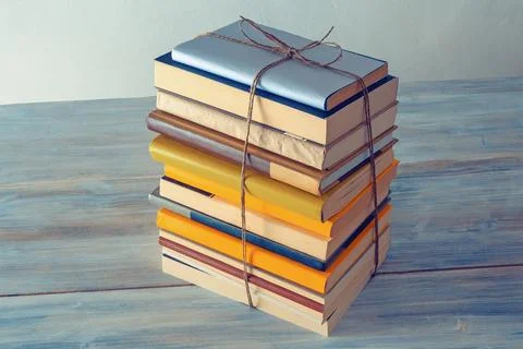 Vertical stack of  books tied with rope on rustic table.  Free space for text Stock Photos