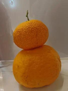 Vertical Stack of Two Ripe Oranges on a White Surface Foto stock