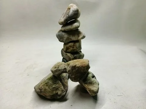 Vertical stack of zen river stones with small rock arch on white background Stock Photos