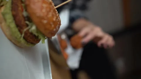 Vertical Static Bokeh Shot Of A Hamburger With Onion Rings On Top With People Stock Footage 252610465
