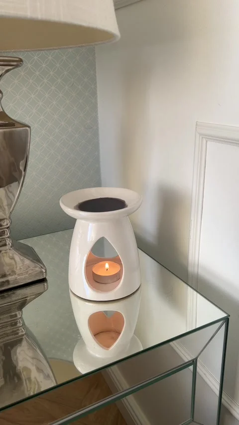 Vertical static close up of ceramic wax burner with burning tealight candle Video stock 346486343