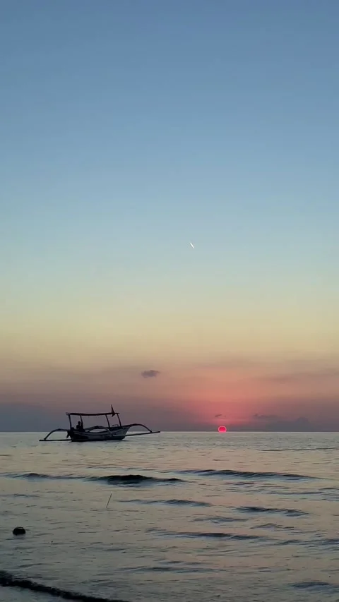 Vertical Static Shot of Boat at Sunset with Contrail in Bali Stock Footage 339276670