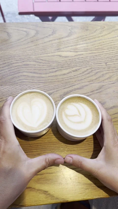 Vertical static shot of couple making heart shape with fingers over coffee cups Stock Footage 336680071