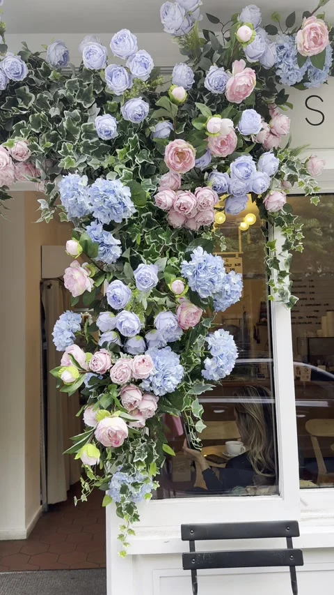 Vertical static shot of flower arch display on shop window with chair Stock Footage 336680203