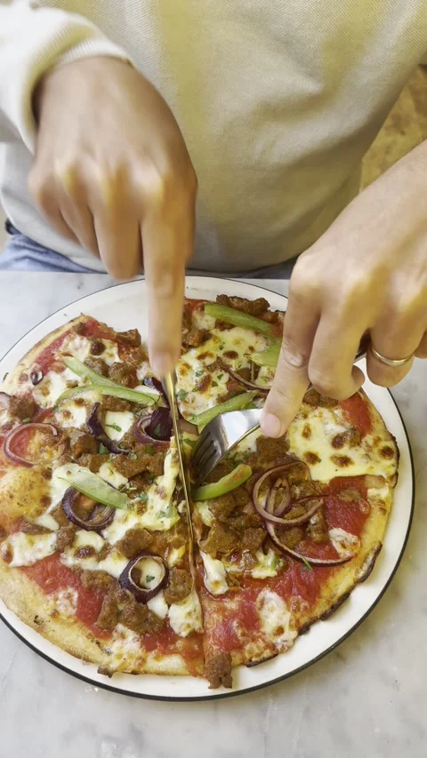 Vertical static shot of male hand cutting whole pizza in half with knife Stock Footage 336865782