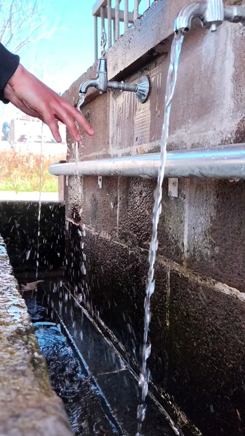 Vertical static shot of a man cupping his hands to drink or collect water from a Vídeos de archivo 334660090