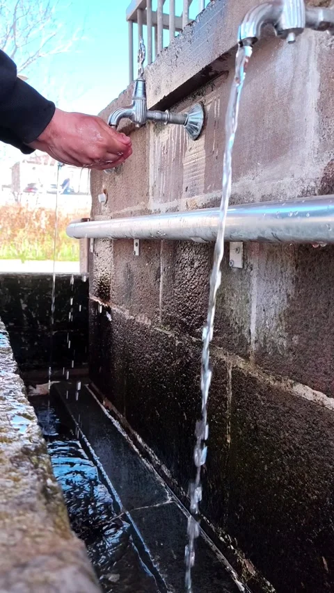Vertical static shot of a man cupping his hands to drink or collect water from a Vídeos de archivo 334660116