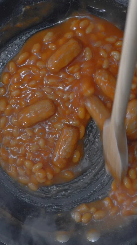Vertical - Stirring steaming hot baked beans and pork sausages in tomato sauce. Stock Footage 292771306