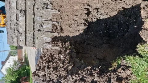 Vertical. On the street, an excavator is digging where a water pipe is leaking. Video stock 277184765
