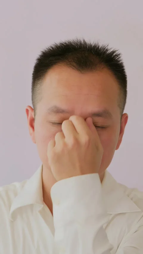 Vertical Stressed and exhausted Asian man massages temples Stock Footage 342471881