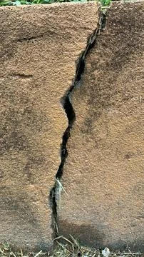 Vertical structural crack running through a textured concrete block wall Foto stock