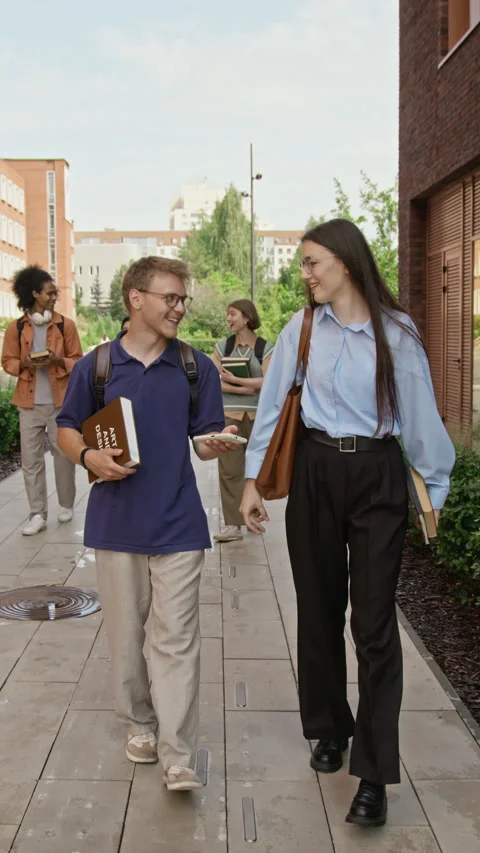 Vertical of Students Walking on Campus and Looking at Smartphone Stock Footage 342123641