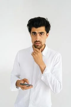 Vertical studio portrait of thinking young man in casual shirt looking at camera Stock Photos