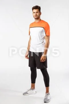Vertical studio shot male football player in activewear, sneakers standing Stock Photos