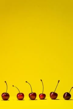 Vertical summer yellow background with red, ripe cherry berries at the bottom. Stock Photos