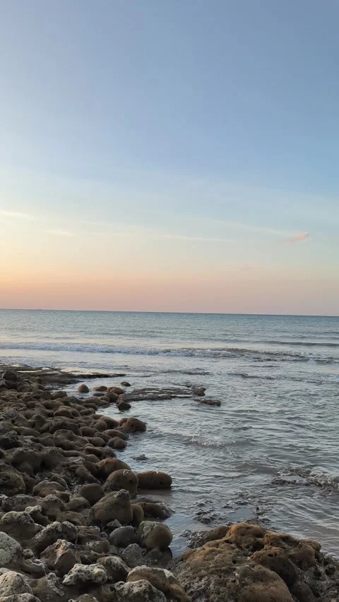 Vertical Sunset Beach Scene with Gentle Ocean Waves and Rocky Coastline Video stock 340489766