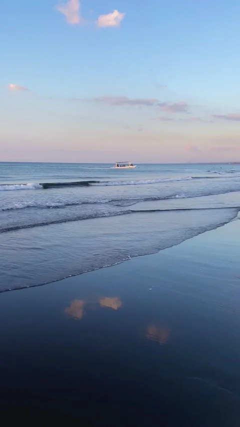 Vertical sunset over Bali beach with waves and distant boat Stock Footage 337857774