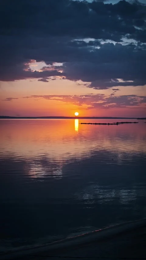 Vertical Sunset Over Calm Lake with Dark Clouds Stock Footage 307684690