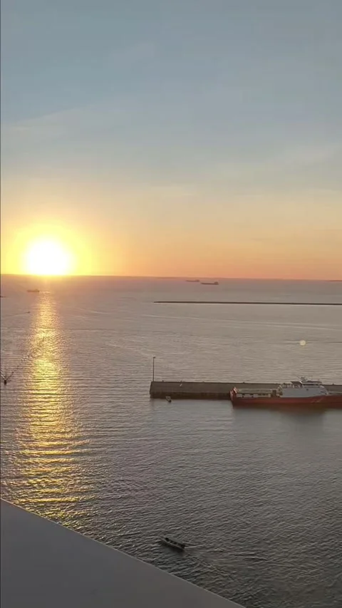 Vertical Sunset Over Calm Sea and Harbor with Golden Reflection Stock Footage 337690283