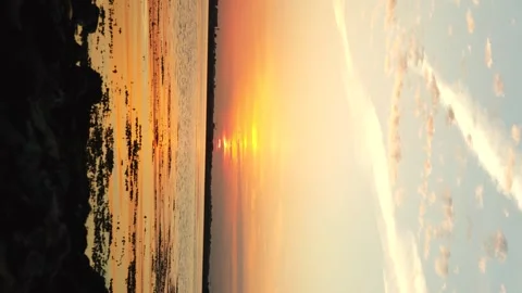 Vertical sunset video with golden reflections across calm sea beneath a warm 動画素材 336690324