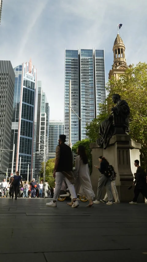 Vertical Sydney crowds pass Queen Victoria Statue next to skyscrapers 6K Stock Footage 306508153