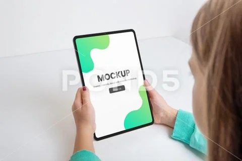 Vertical tablet held by a girl on a work desk mockup PSD Template