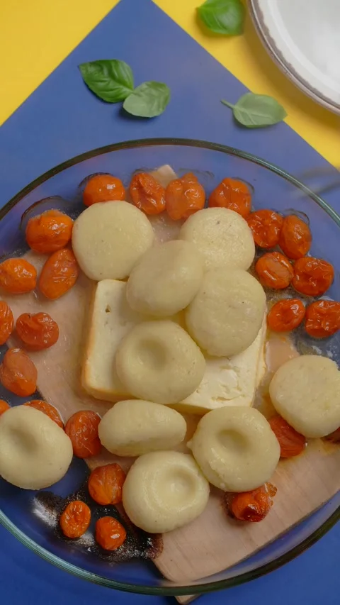 Vertical tabletop video: chef adds cooked potato dumplings to the baked tomatoes Stock Footage 180137319