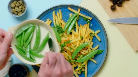 Vertical tabletop video: chef adds sweet pea pods to the fried potato dish Stock Footage 180572350