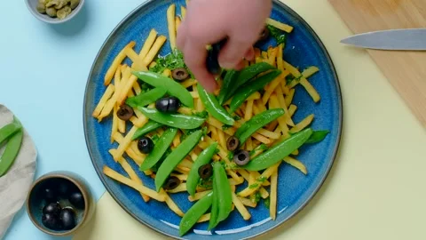 Vertical tabletop video: chef adds black olives to the fried potato dish Stock Footage 180572575