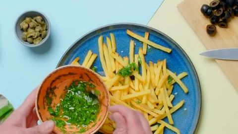 Vertical tabletop video: chef adds green sauce to the fried potato dish Video stock 181108015