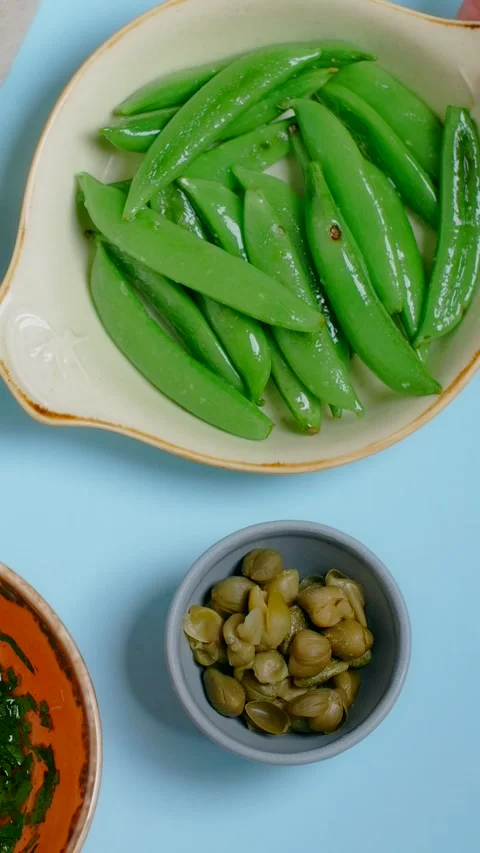 Vertical tabletop video: chef puts plate with coocked sweet pea pods to the Stock Footage 179408013