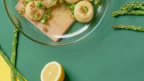 Vertical tabletop video: chef takes cooked potato dumpling with baked asparagus Video stock 184448208