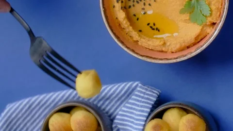 Vertical tabletop video: man scoops up hummus with crispy fried potato balls Stock Footage 183870779